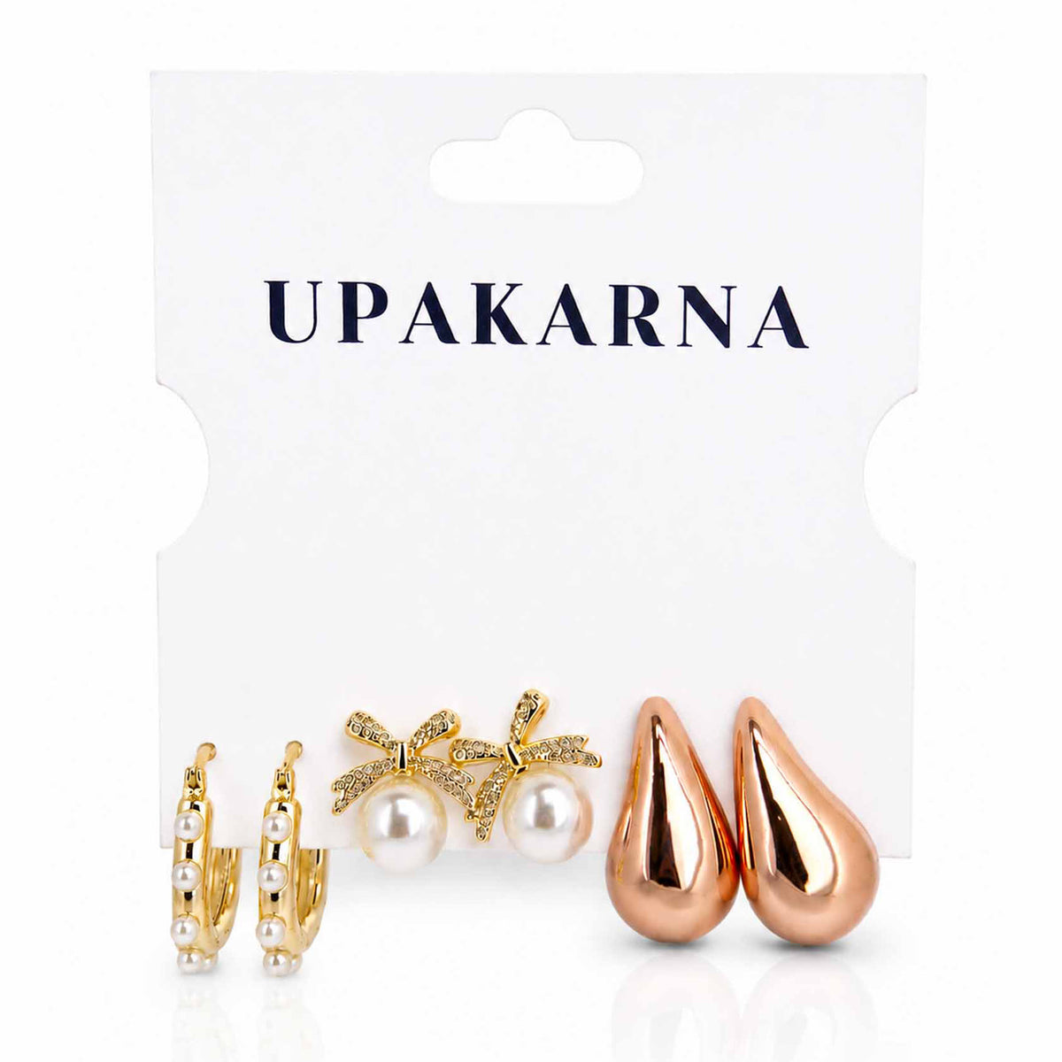 Stylish mixed-metal earring stack featuring rose gold teardrop studs, pearl bow studs and gold pearl-lined hoop earrings.