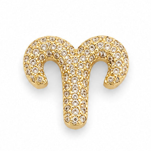 Gold-tone Aries zodiac charm featuring the iconic ram-horn symbol with two symmetrical curved horns and a central vertical stem. The charm is densely embellished with numerous small white rhinestones, creating a bright, sparkling textured surface. It has polished gold-tone edges, raised detailing, and a smooth dimensional finish, isolated against a clean white background.
