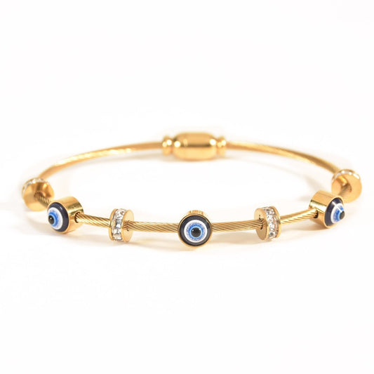 Gold evil eye cable bangle featuring blue enamel evil eye charms, sparkling crystal spacer beads, and a sleek twisted cable design. Finished with an anti-tarnish coating and displayed on a clean white background, this adjustable bracelet.
