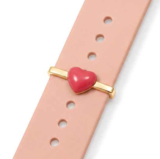 Heart watch charm with a glossy red heart motif attached to a peach-coloured watch strap.