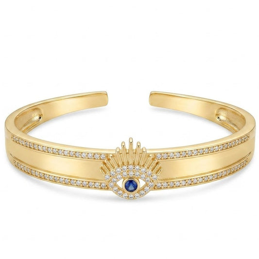 Anti-tarnish yellow gold open cuff bracelet featuring a central sunburst eyelash evil eye motif with a blue sapphire crystal center, surrounded by clear pavé cubic zirconia borders on a smooth flat band.