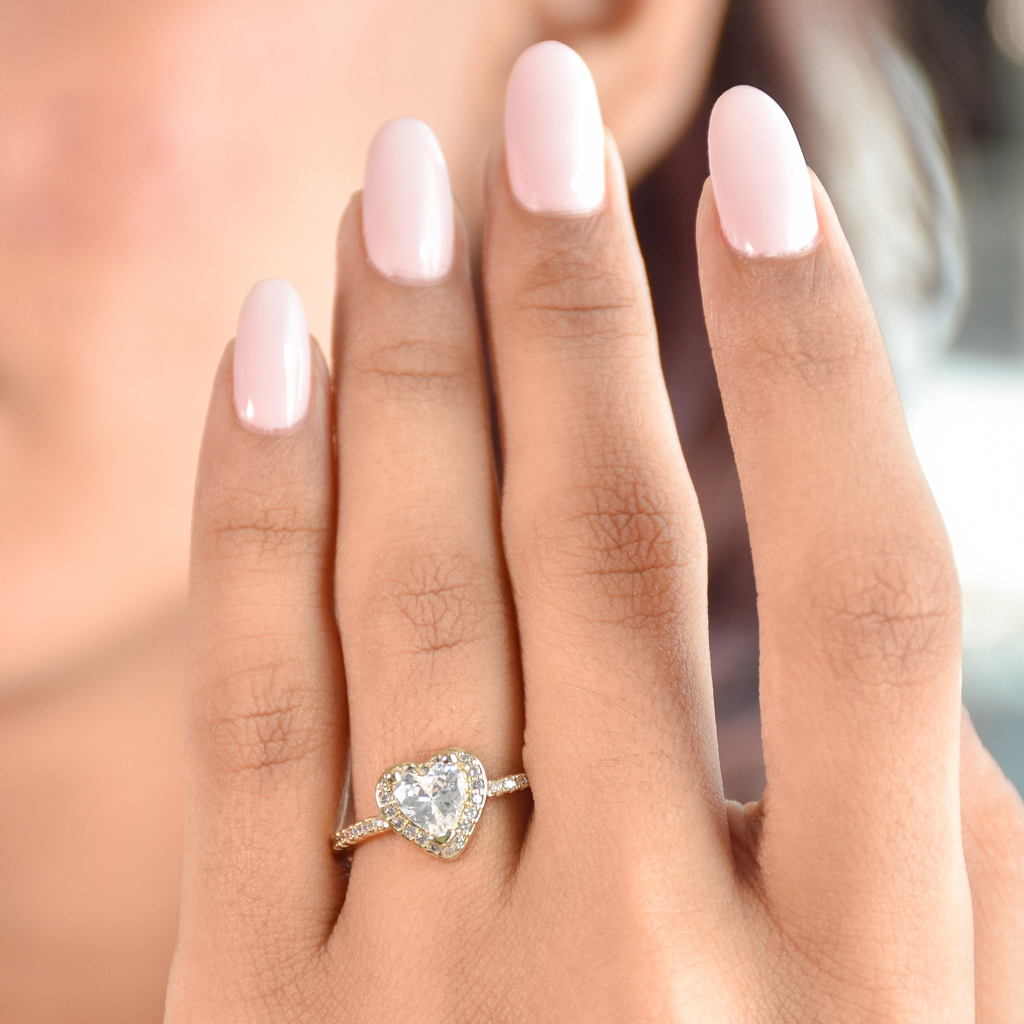 A stack of three adjustable gold rings featuring a heart-shaped crystal, an emerald-green stone, and a sparkling oval nail-head band.