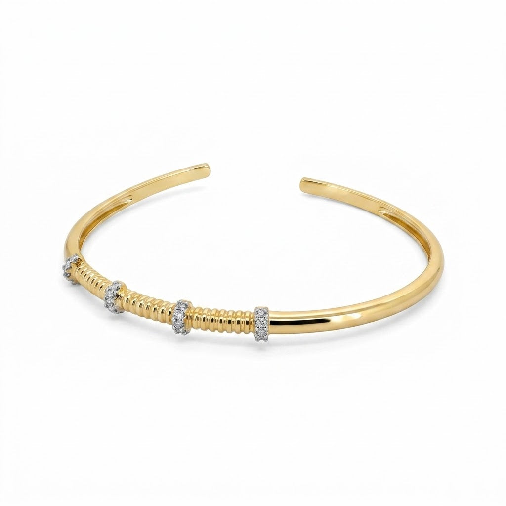 Anti-tarnish yellow gold open cuff bracelet with a central fluted ribbed section and silver-tone pavé cubic zirconia spacer bands, isolated on a solid white background.