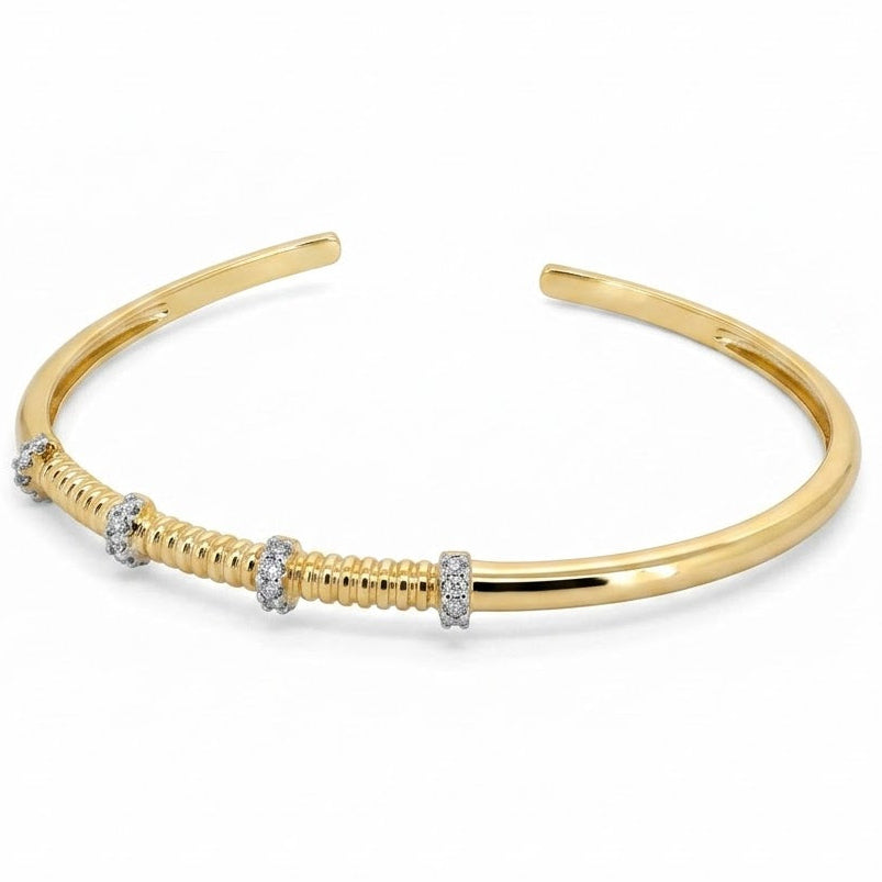 Anti-tarnish yellow gold open cuff bracelet with a central fluted ribbed section and silver-tone pavé cubic zirconia spacer bands, isolated on a solid white background.