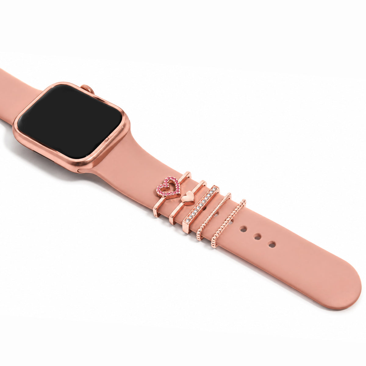 Zoomed-out view of a rose gold smartwatch with a pink strap decorated with a pink crystal heart charm, heart charm, pavé crystal bar, and delicate chain-style bands on a white background.