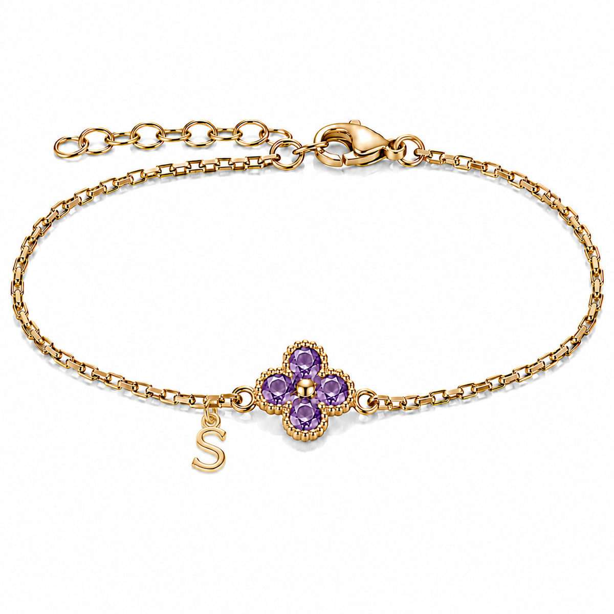 Gold-plated bracelet featuring a delicate four-leaf clover charm with four rich purple stones and a dangling gold-tone “S” initial charm, set on a fine gold chain with an adjustable extension chain and lobster clasp, displayed against a clean white background.