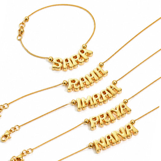 Gold-plated personalized name bracelets arranged diagonally on a white background, featuring names such as Sara, Rahh, Imanh, Priya, and Nana on delicate chain bracelets.