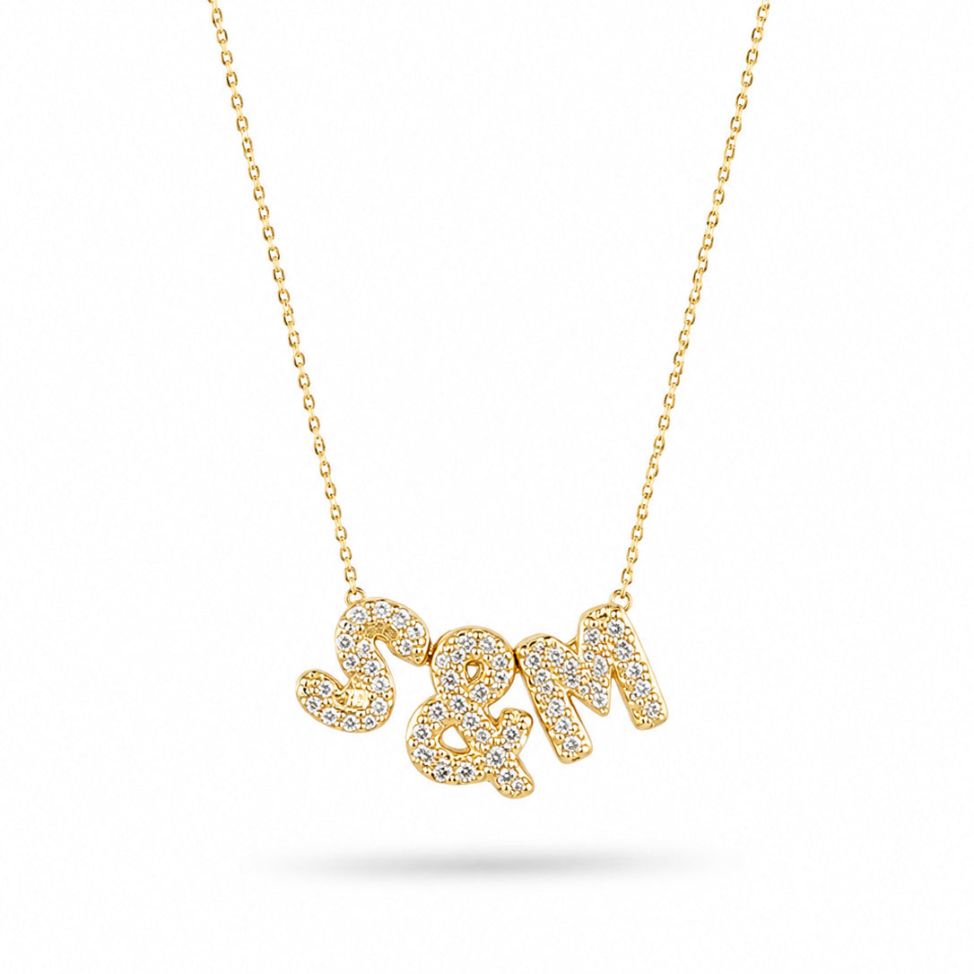 Gold-plated personalized necklace featuring sparkling pavé initials “S & M” on a delicate chain, displayed on a clean white background.