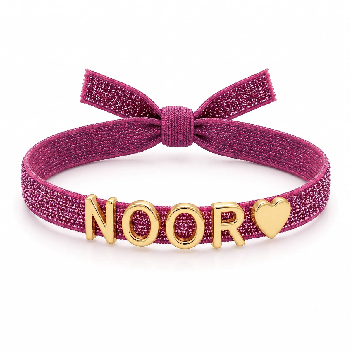 Pink glittery adjustable bracelet featuring a large bow detail and gold-tone NOOR letter charms with a heart charm at the end.