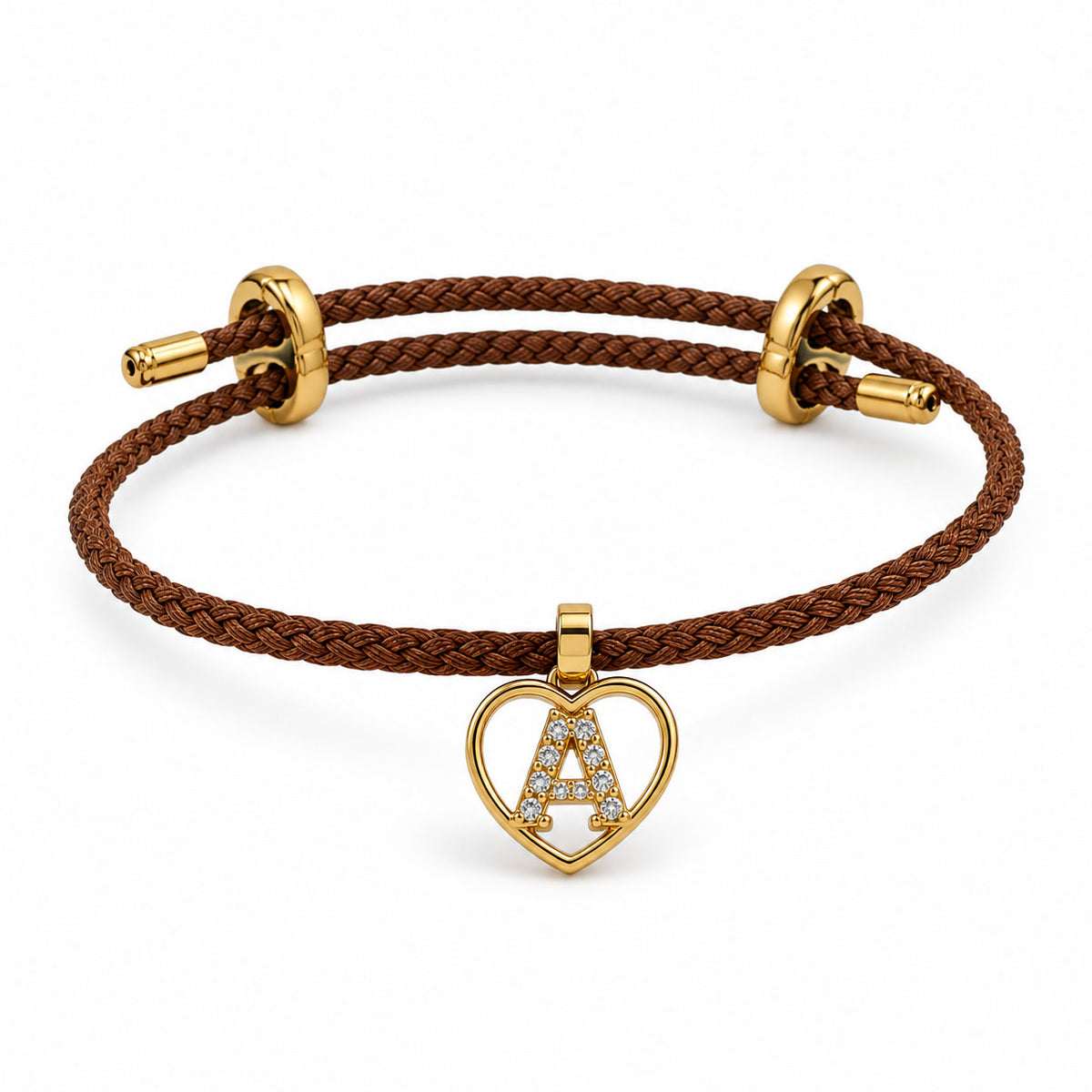 Brown braided cord bracelet with gold-tone metal fittings and a heart-shaped initial “A” charm embellished with clear crystals, displayed on a clean white background.