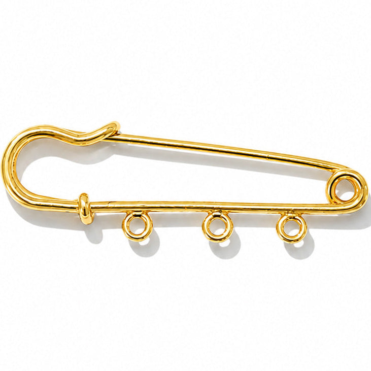 Gold-tone safety pin charm holder with three attachment loops for adding interchangeable charms, displayed on a clean white background.