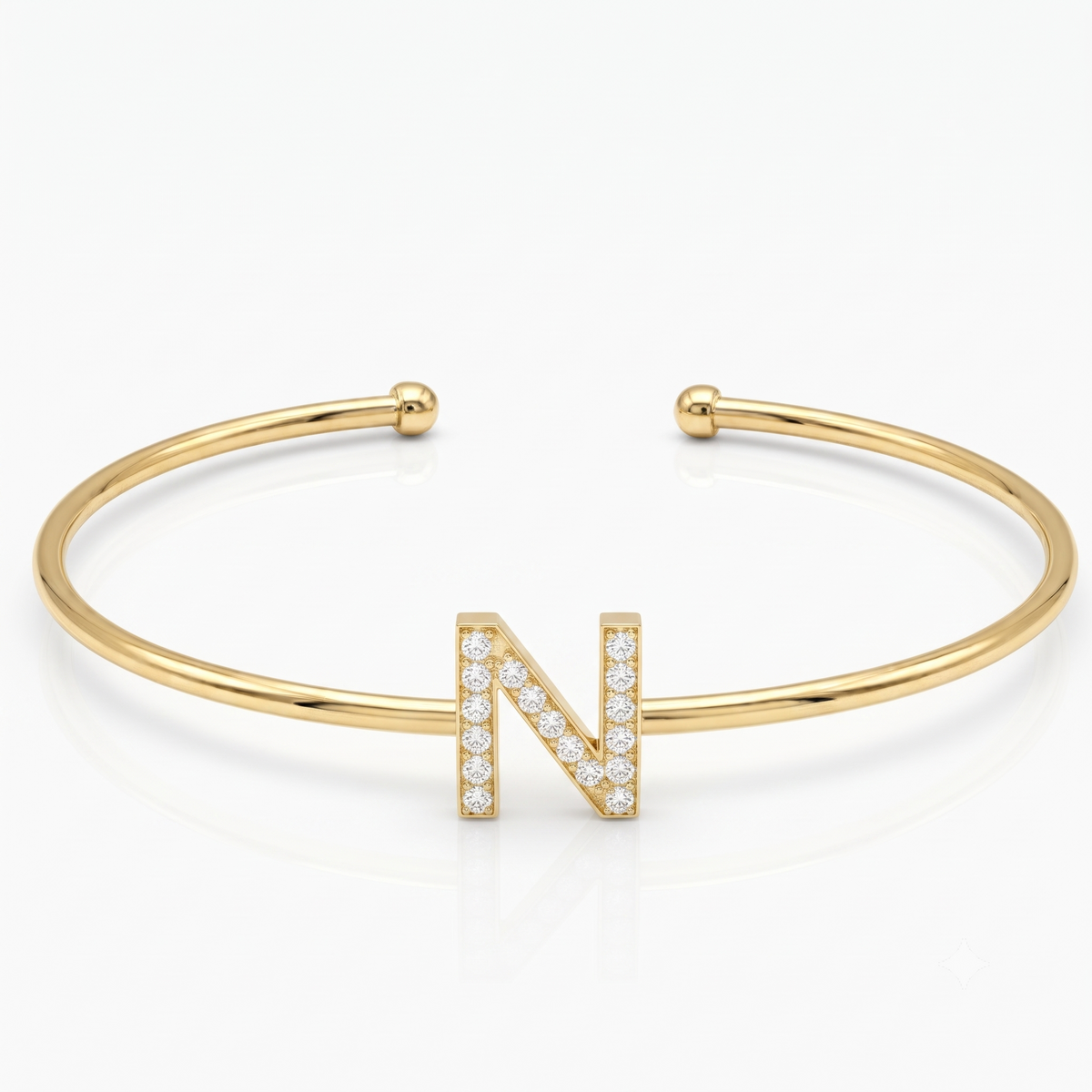 Elegant gold-tone adjustable open cuff bangle featuring a pavé crystal-studded letter N centerpiece. The personalized initial bangle has a sleek polished finish with rounded ball ends and is displayed on a clean white background, making it perfect for everyday wear, stacking, gifting, and personalized jewellery collections.