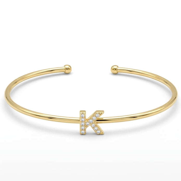 Elegant gold-tone adjustable open cuff bangle featuring a pavé crystal-studded letter K centerpiece. The personalized initial bangle has a sleek polished finish with rounded ball ends and is displayed on a clean white background, making it perfect for everyday wear, stacking, gifting, and personalized jewellery collections.