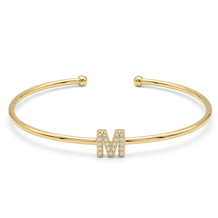 Elegant gold-tone adjustable open cuff bangle featuring a pavé crystal-studded letter M centerpiece. The personalized initial bangle has a sleek polished finish with rounded ball ends and is displayed on a clean white background, making it perfect for everyday wear, stacking, gifting, and personalized jewellery collections.