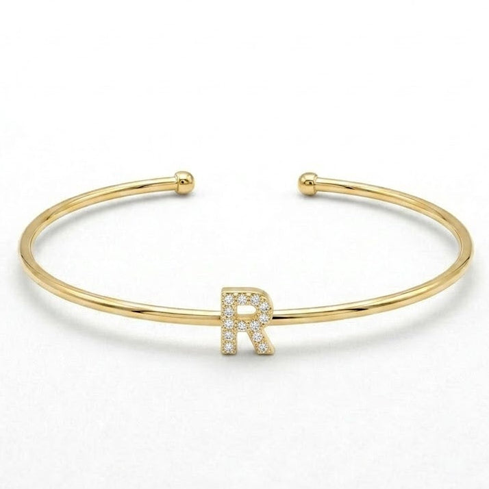 Elegant gold-tone adjustable open cuff bangle featuring a pavé crystal-studded letter R centerpiece. The personalized initial bangle has a sleek polished finish with rounded ball ends and is displayed on a clean white background, making it perfect for everyday wear, stacking, gifting, and personalized jewellery collections.