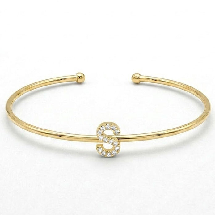 Elegant gold-tone adjustable open cuff bangle featuring a pavé crystal-studded letter S centerpiece. The personalized initial bangle has a sleek polished finish with rounded ball ends and is displayed on a clean white background, making it perfect for everyday wear, stacking, gifting, and personalized jewellery collections.