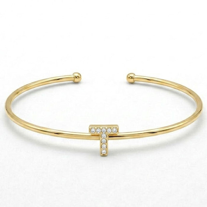 Elegant gold-tone adjustable open cuff bangle featuring a pavé crystal-studded letter T centerpiece. The personalized initial bangle has a sleek polished finish with rounded ball ends and is displayed on a clean white background, making it perfect for everyday wear, stacking, gifting, and personalized jewellery collections.