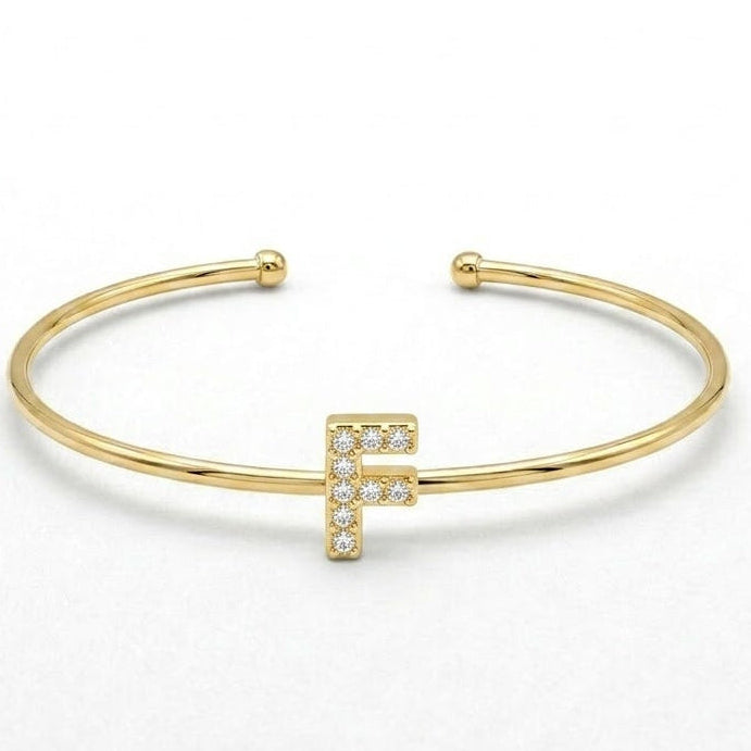 Elegant gold-tone adjustable open cuff bangle featuring a pavé crystal-studded letter F centerpiece. The personalized initial bangle has a sleek polished finish with rounded ball ends and is displayed on a clean white background, making it perfect for everyday wear, stacking, gifting, and personalized jewellery collections.
