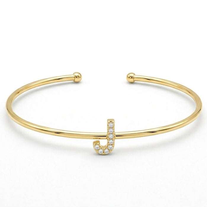 Elegant gold-tone adjustable open cuff bangle featuring a pavé crystal-studded letter J centerpiece. The personalized initial bangle has a sleek polished finish with rounded ball ends and is displayed on a clean white background, making it perfect for everyday wear, stacking, gifting, and personalized jewellery collections.