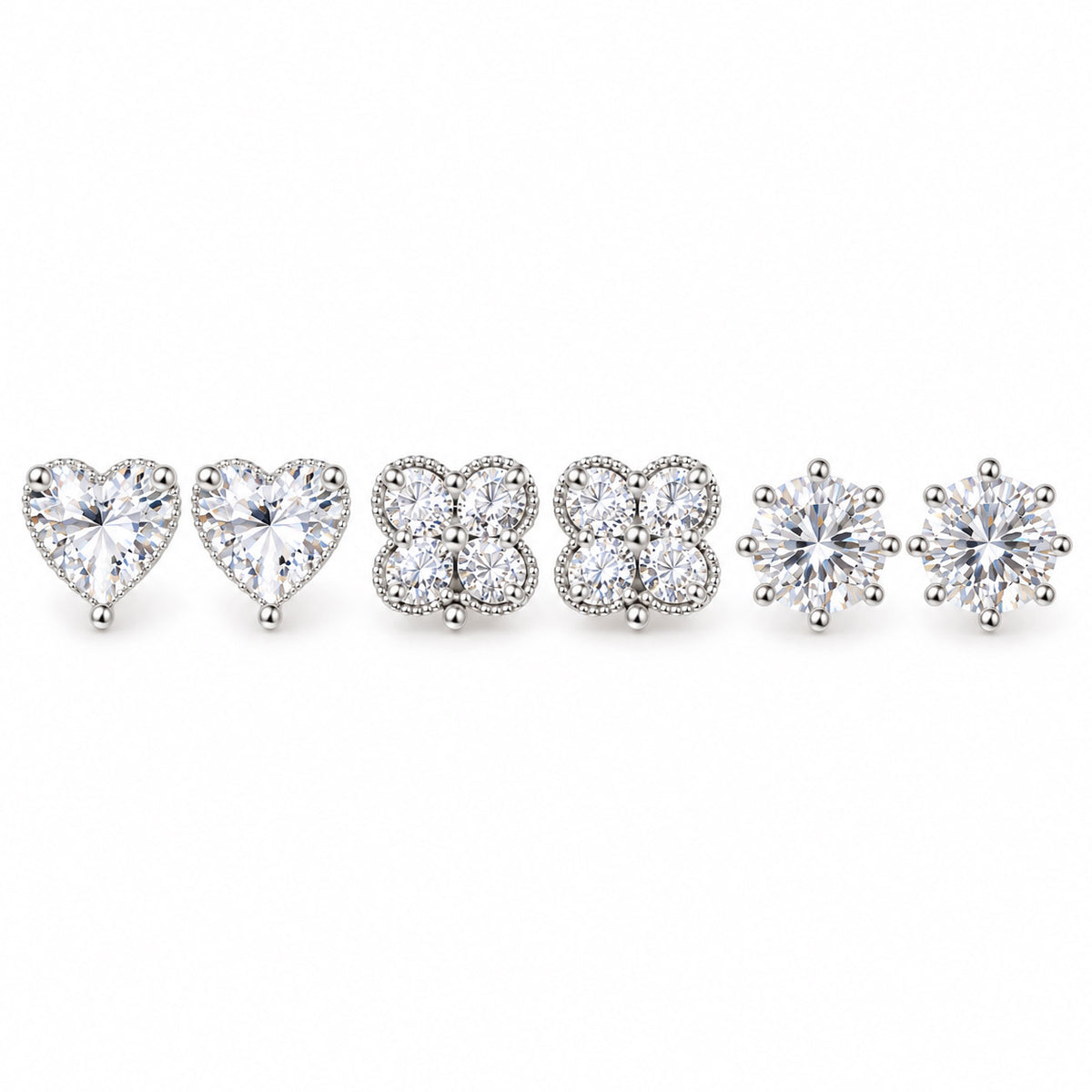 Three pairs of silver-tone crystal stud earrings featuring sparkling heart-shaped, four-petal floral cluster, and classic round solitaire designs, arranged on a clean white background with a polished premium finish.