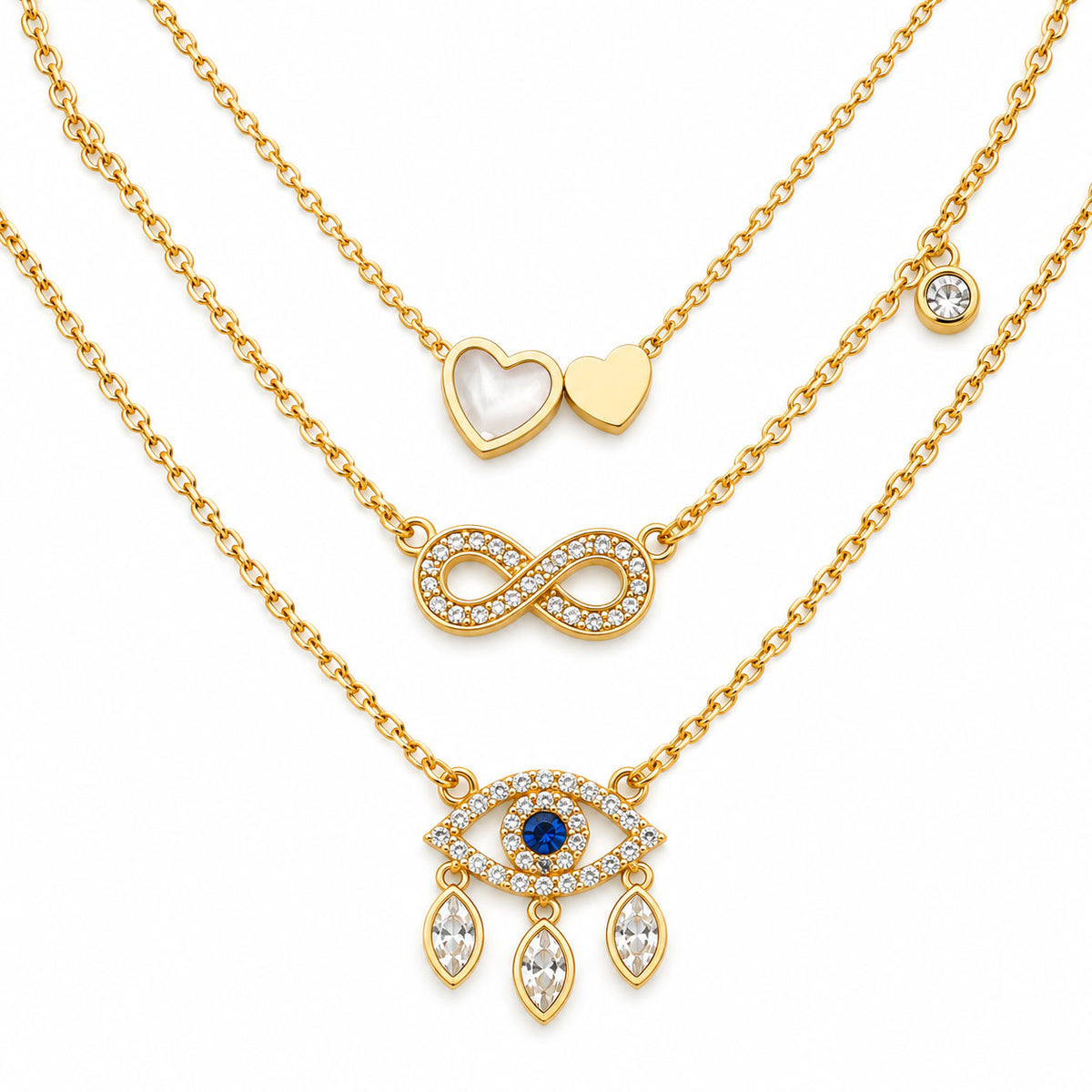 Upakarna gold necklace set featuring three layered necklaces with a heart pendant, crystal infinity pendant, and evil eye pendant with dangling crystals on a clean white background.
