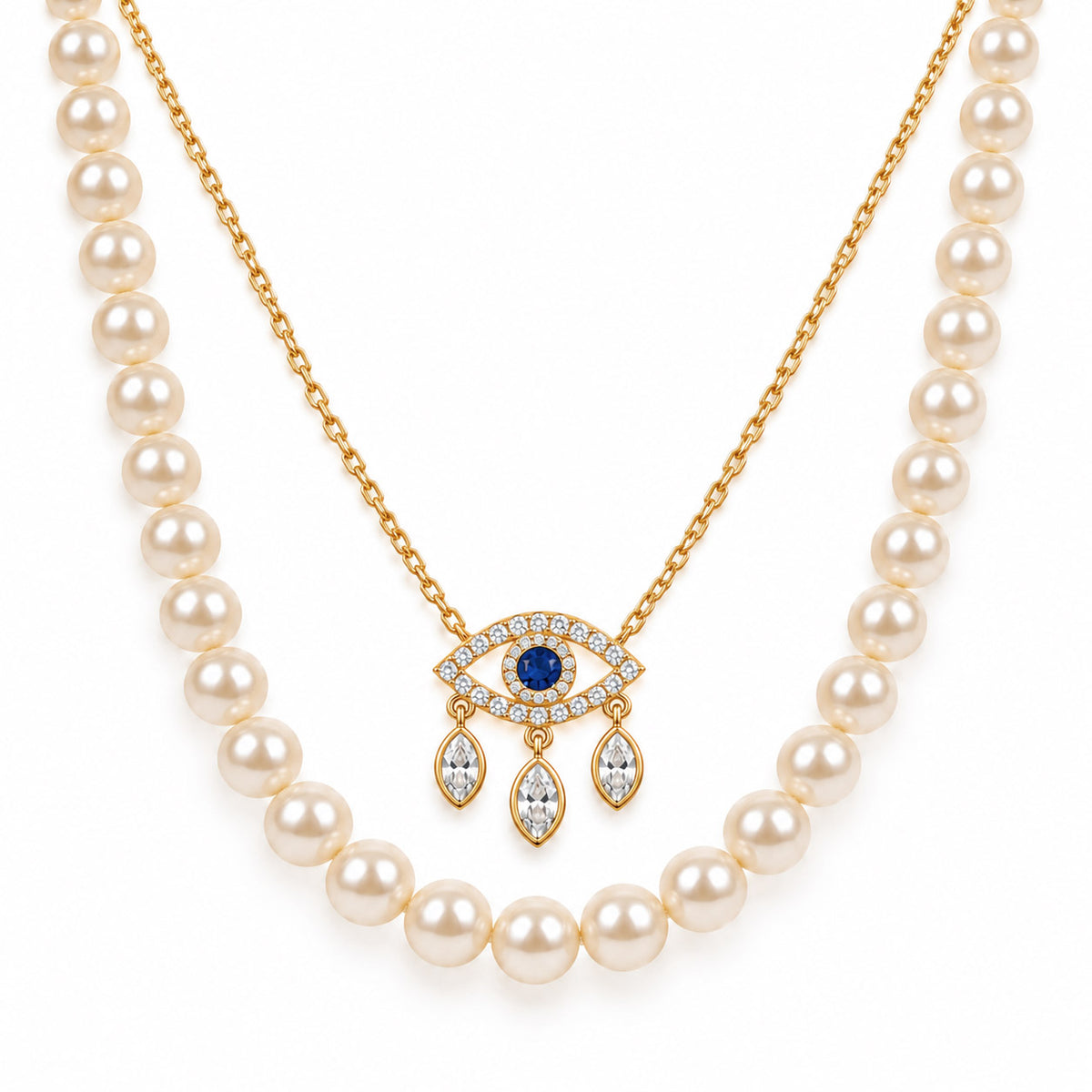 A product photo of a layered gold-tone necklace set featuring a classic white pearl strand paired with a delicate link chain holding an evil eye pendant adorned with crystal pave and dangling marquise stones.   
