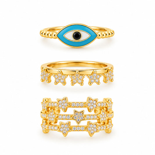 Three gold rings featuring a turquoise evil eye ring, a sparkling star charm ring, and a bold multi-band pavé star ring on a clean white background.
