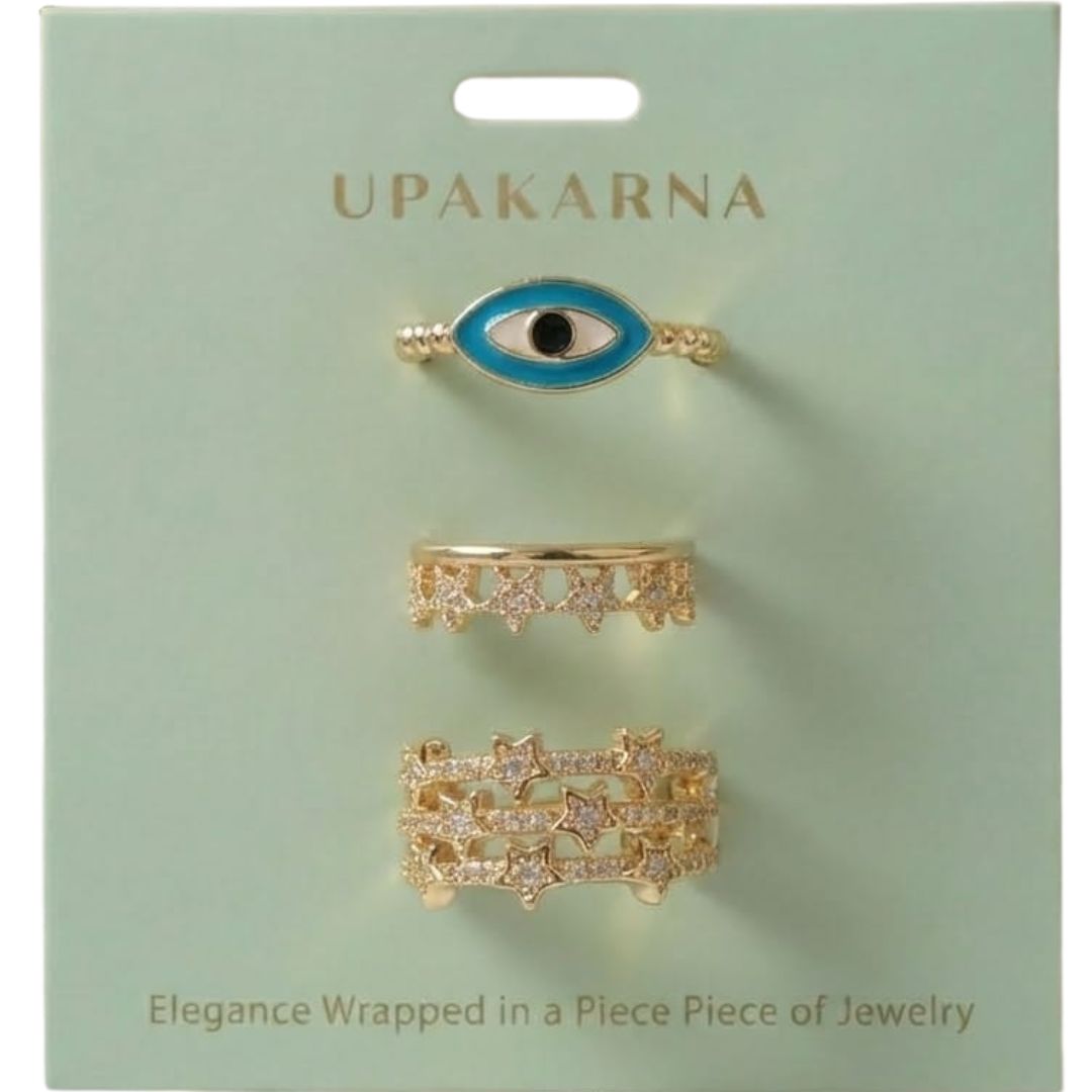 A trio of adjustable gold-toned rings stacked together, featuring a pastel evil eye centerpiece, a sparkling stardust band, and a delicate star-inspired ring.
