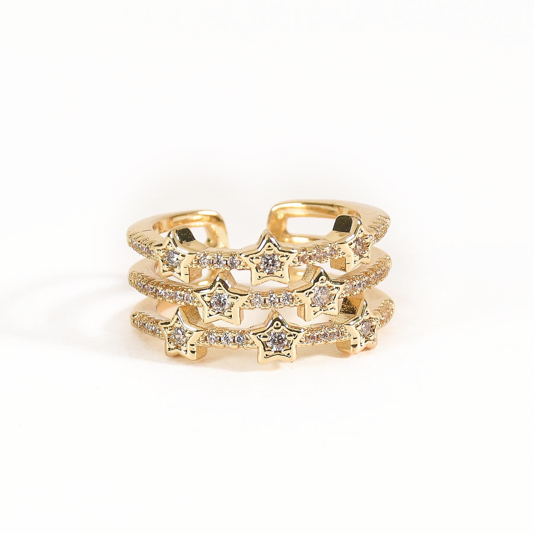 A trio of adjustable gold-toned rings stacked together, featuring a pastel evil eye centerpiece, a sparkling stardust band, and a delicate star-inspired ring.