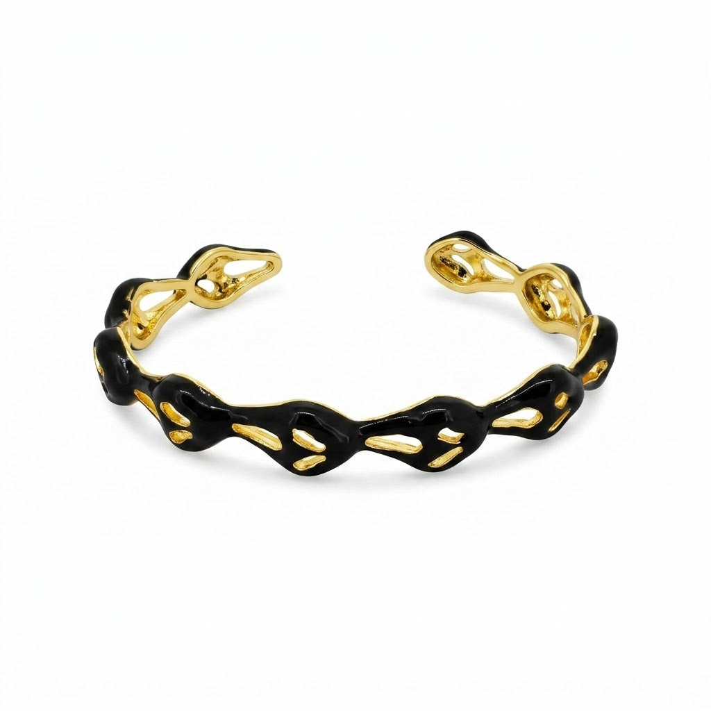 Anti-tarnish yellow gold open cuff bracelet featuring a wavy, fluid openwork band coated in glossy black enamel with teardrop-shaped hollow cutouts.