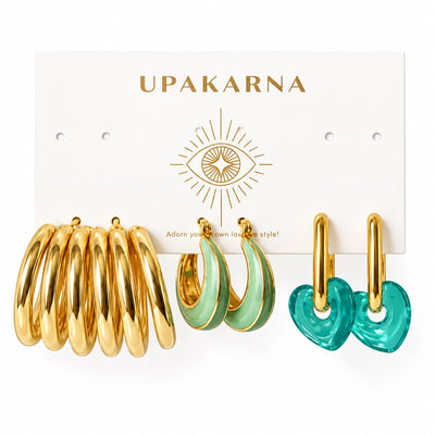 Three pairs of statement hoop earrings displayed on an Upakarna jewellery card, featuring chunky gold tube hoops, mint green teardrop enamel hoops with gold edges, and translucent teal heart drop hoops with gold-plated hoops, arranged on a clean white background with a premium polished finish.