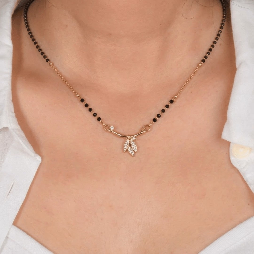 Golden arc mangalsutra necklace with bamboo-inspired bar and pavé leaf pendant in a minimal modern design