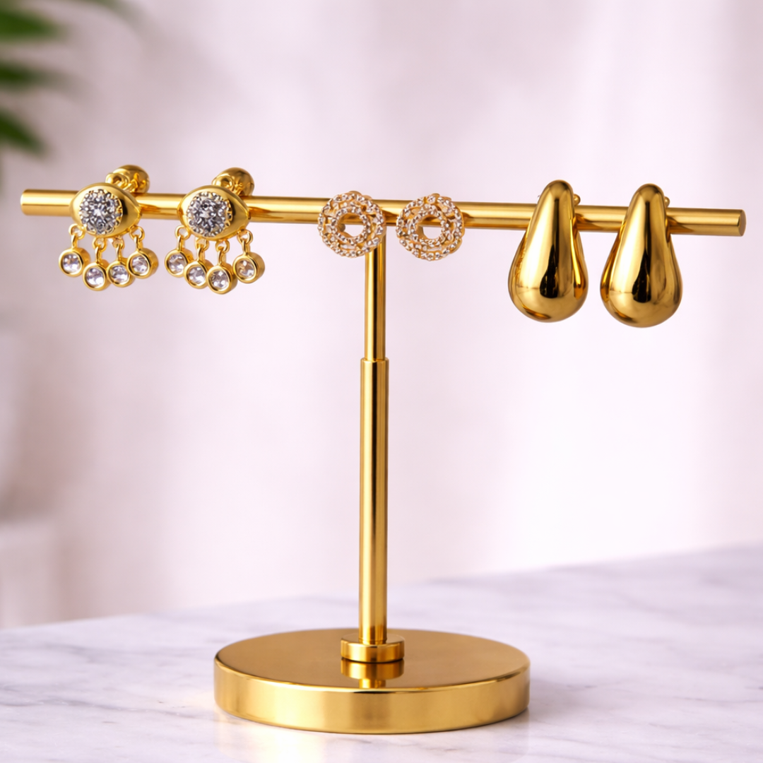 Trendy gold earrings with tear drop shapes, evil eye detail, and minimal stud earrings