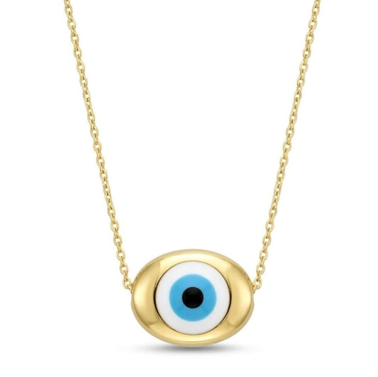 A gold necklace with a horizontally oriented oval charm attached directly to a fine chain. The smooth gold setting frames a classic Evil Eye motif with a black pupil, light blue iris, and white ring, centered on a plain white square background with a dark border.