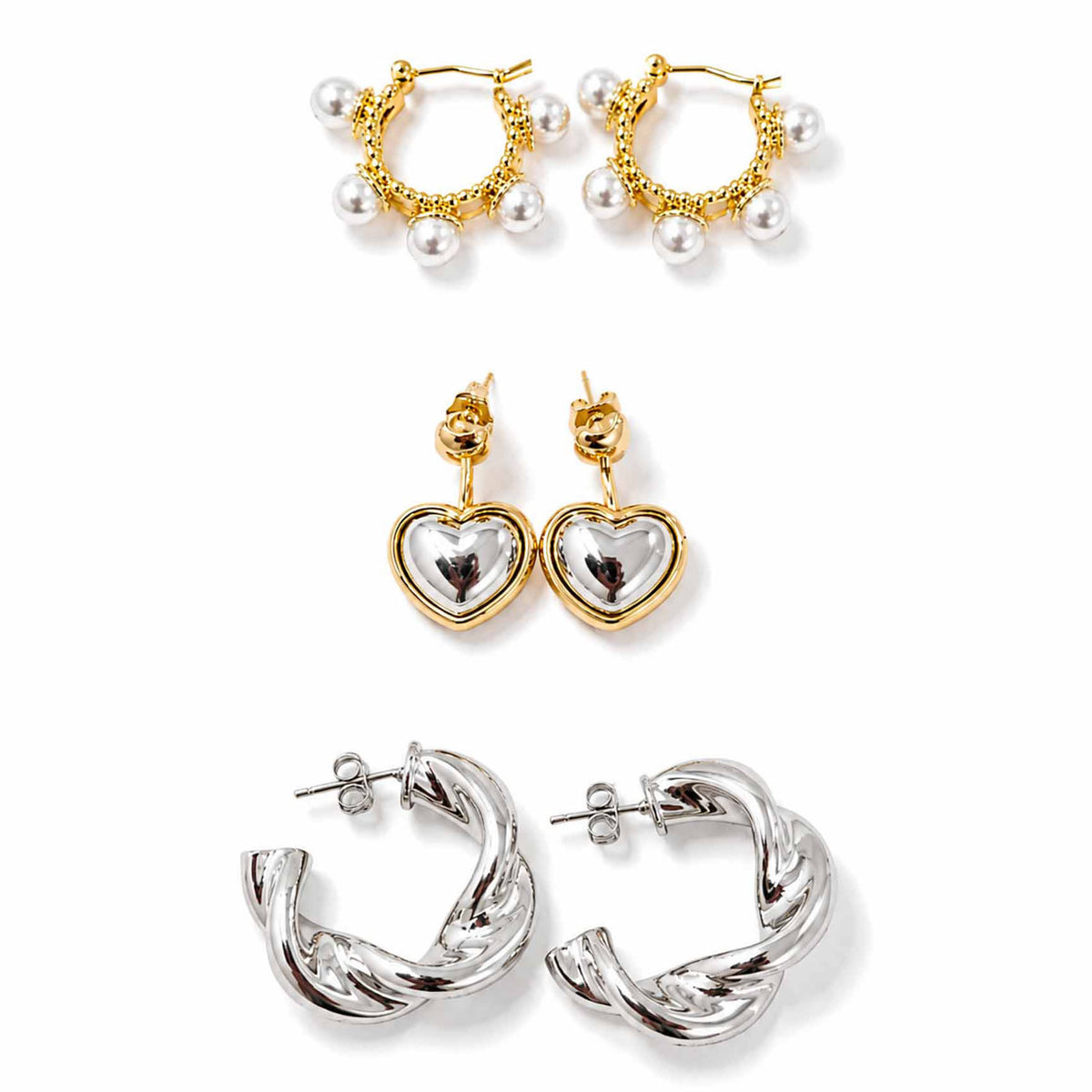 Gold, silver and pearl earring stack featuring pearl-detailed hoops, two-tone heart drop earrings and sculptural twisted silver hoops, displayed on a clean white background.