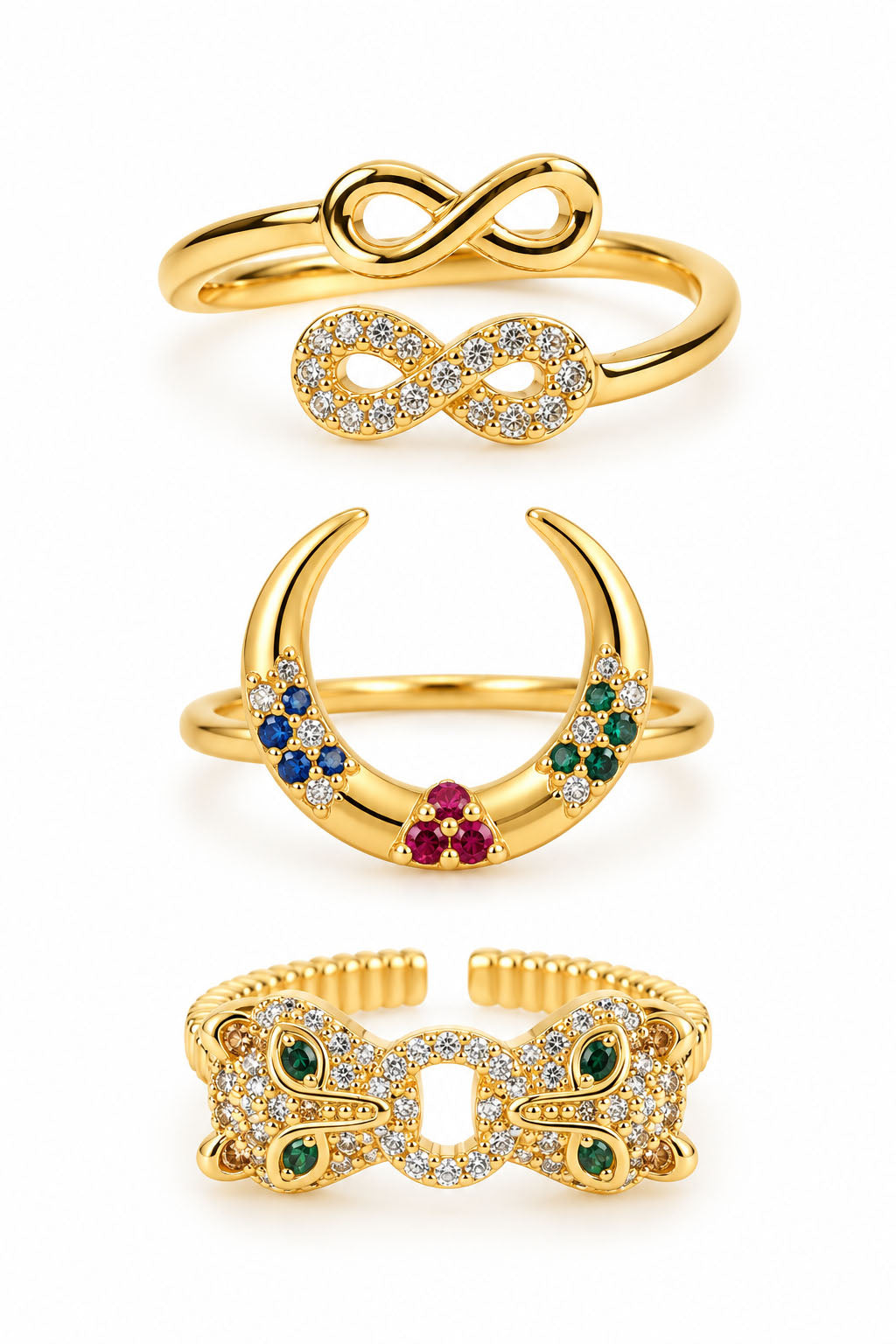 Three gold statement rings featuring an infinity duo ring, a colorful crescent crystal ring, and a bold butterfly-inspired pavé ring with green gemstone accents on a clean white background.
