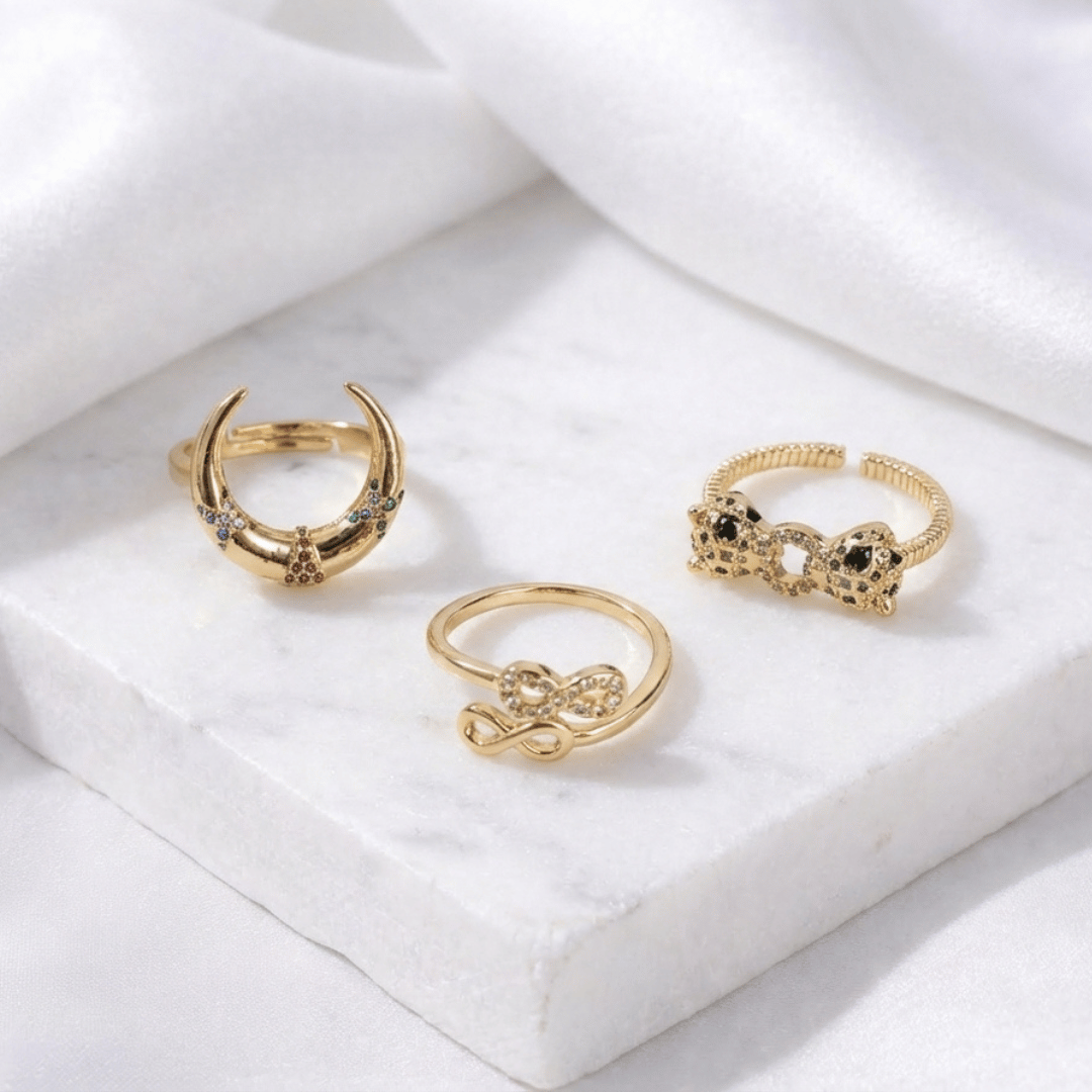 A stacked set of three adjustable gold-toned rings featuring a tiger head motif, a woven infinity band, and a fluid horseshoe-shaped ring.