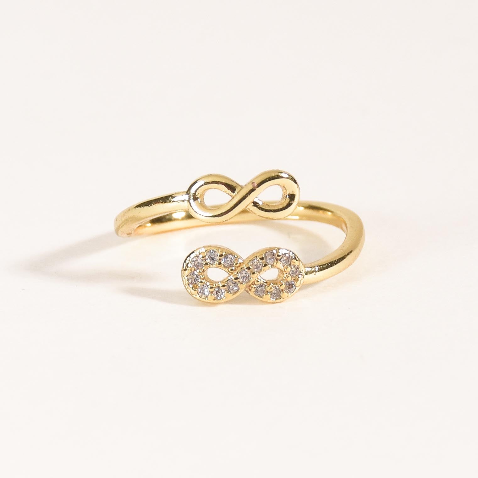 A stacked set of three adjustable gold-toned rings featuring a tiger head motif, a woven infinity band, and a fluid horseshoe-shaped ring.