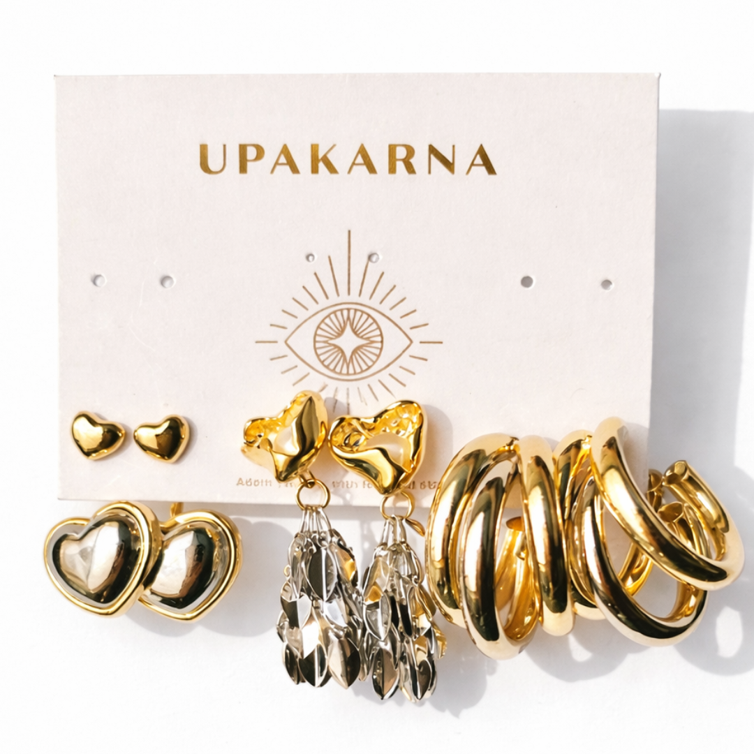 Gold earring stack with triple hoops, heart drop earrings, and cascading leaf design earrings with crystal details