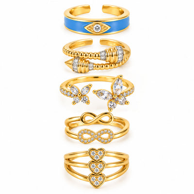 Five gold rings featuring a blue evil eye enamel ring, a bold wraparound beaded ring, a sparkling butterfly open ring, a layered infinity ring set, and a triple-heart pavé ring on a clean white background.