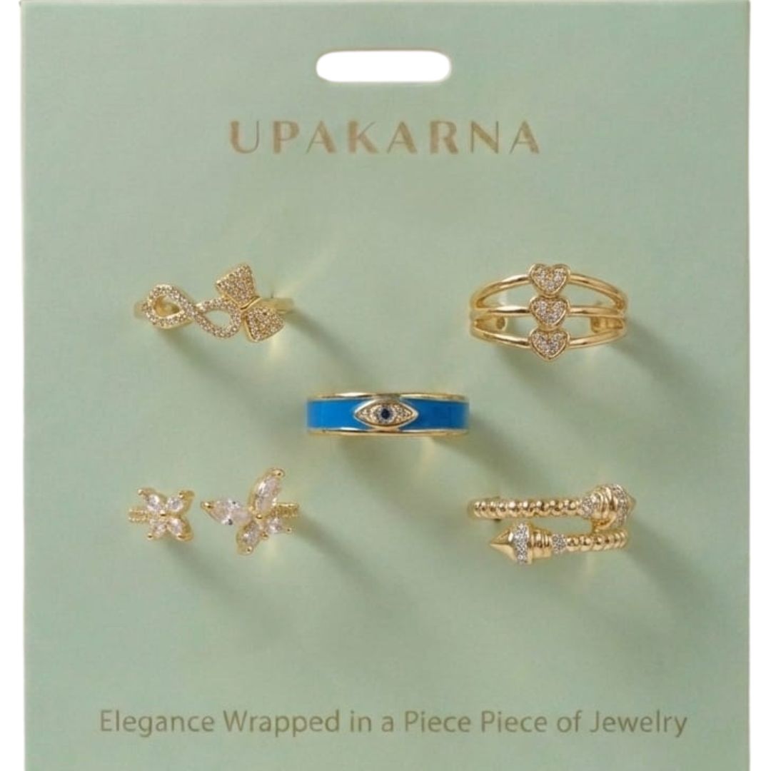 Set of five adjustable gold rings featuring an infinity bow, triple hearts, a textured coil, an enamel butterfly, and a crystal evil eye.