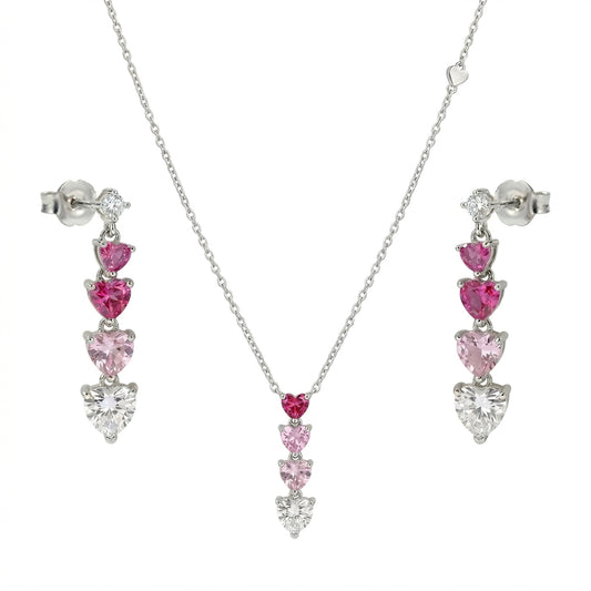 Silver heart pendant necklace and drop earring set featuring pink and clear heart-cut crystals, displayed on a white background