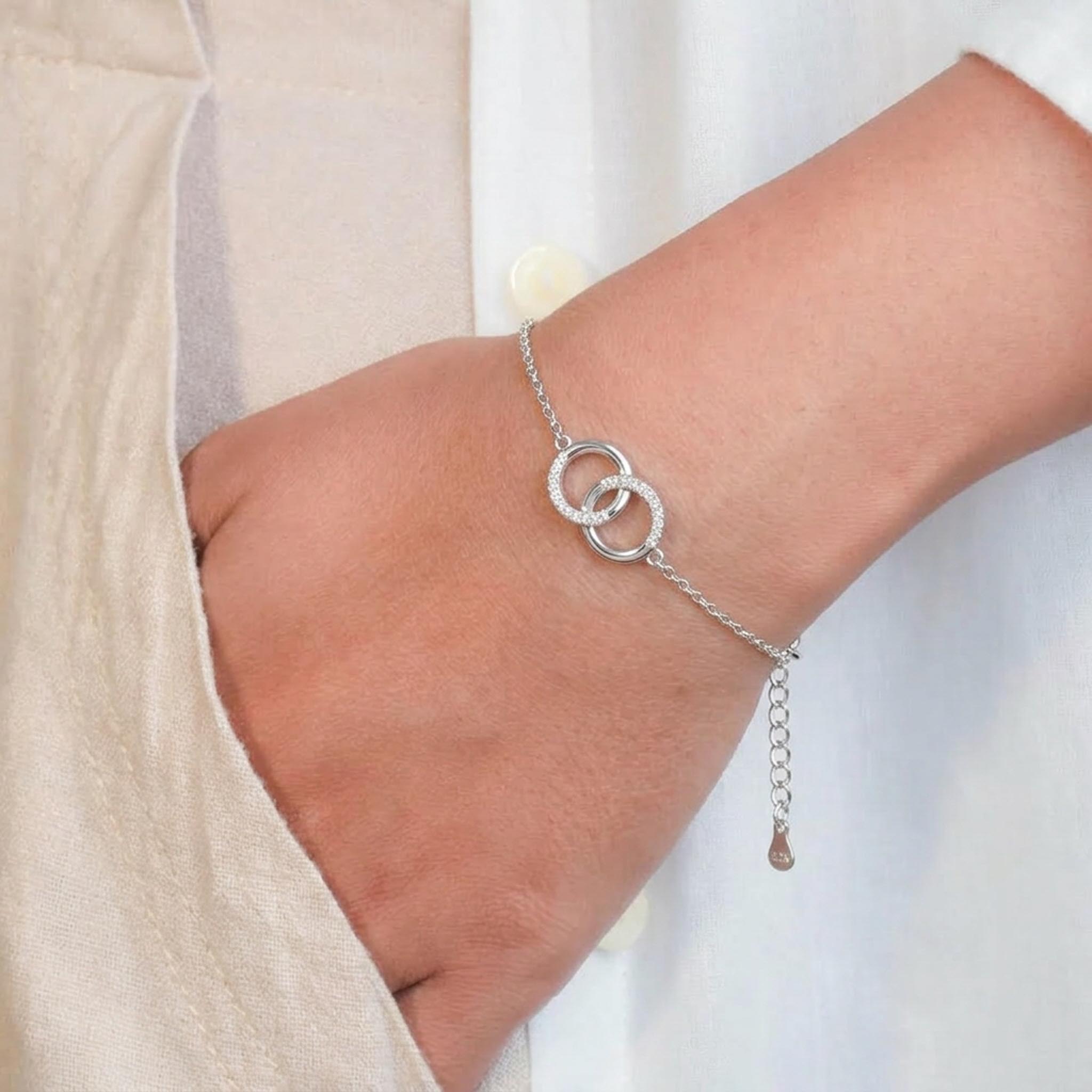 Intertwined Link 925 Sterling Silver Bracelet featuring two elegantly interlocking circular rings, one adorned with sparkling pave-set stones, suspended from a delicate sterling silver chain