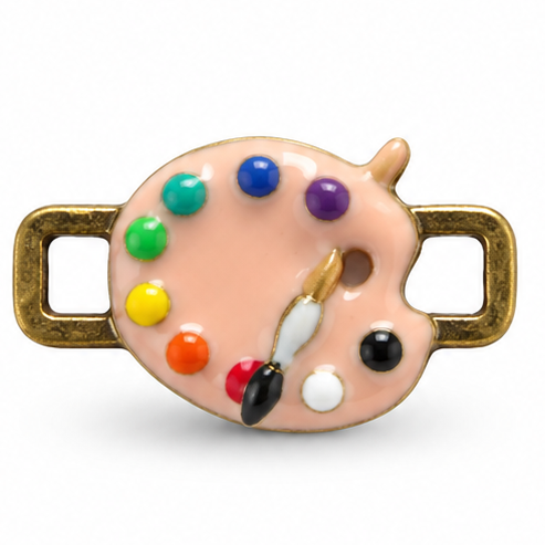 Detailed artist palette jewellery charm featuring a glossy peach-colored painter’s palette with a thumb hole, six colorful paint blobs in green, turquoise, blue, purple, yellow, orange, red, white, and black, plus a small paintbrush resting diagonally across the palette. Textured antique-gold rectangular loops extend horizontally from both sides.