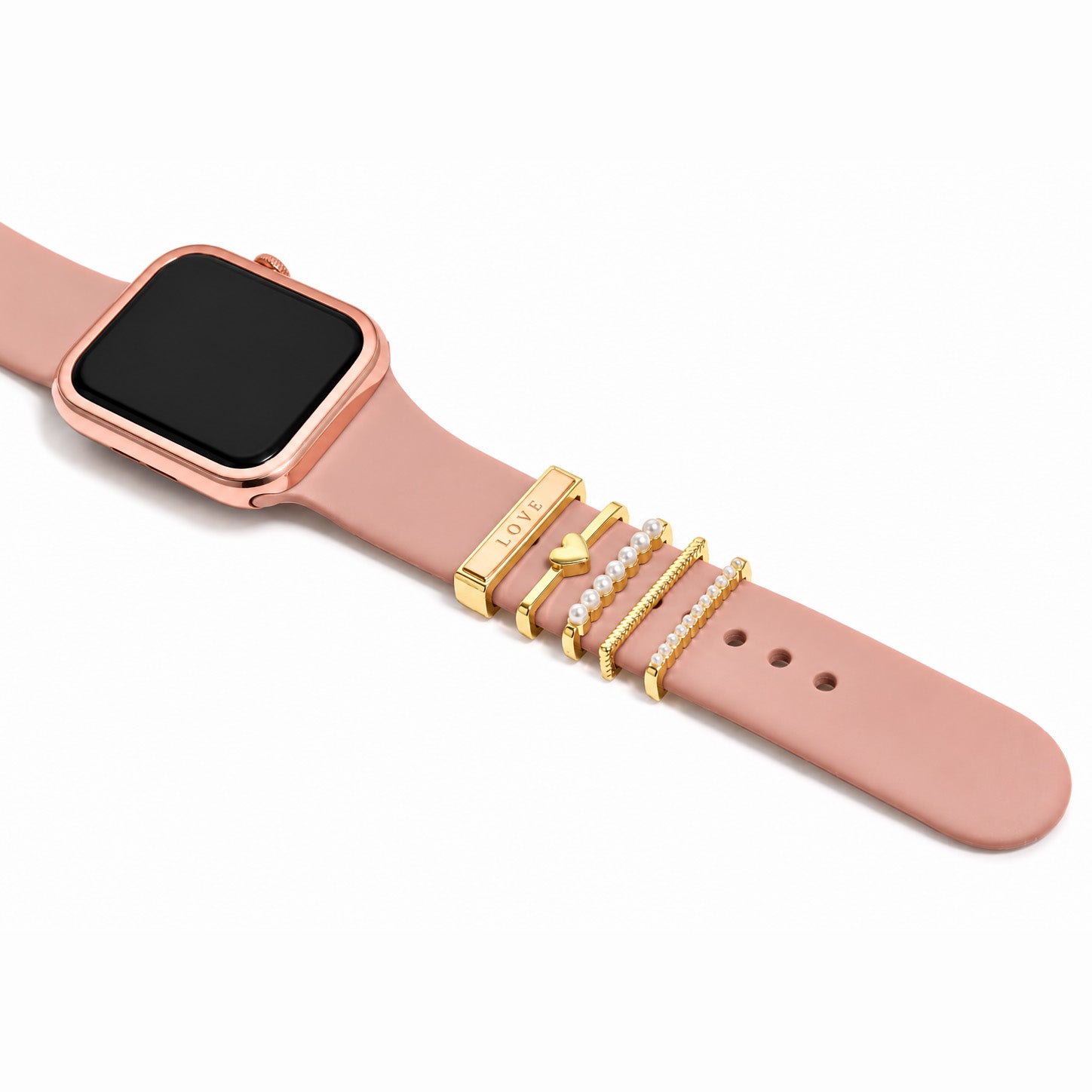 Zoomed-out view of gold-tone watch charms featuring a LOVE charm, heart charm, pearl accents, textured chain detail, and pearl-lined design on a blush pink watch strap against a clean white background.