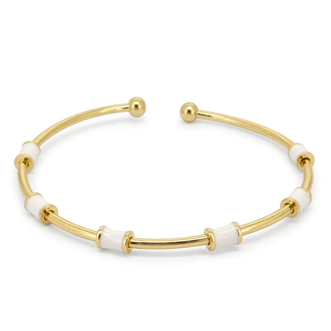 Anti-tarnish yellow gold open cuff bracelet featuring a slender polished band set with cylindrical white enamel station tubes and smooth spherical ball terminals, on a solid white background.