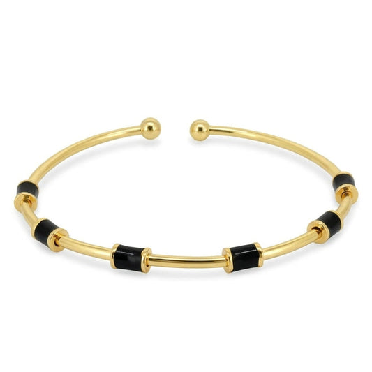 Anti-tarnish yellow gold open cuff bracelet featuring a slender polished band set with cylindrical black enamel station tubes and smooth spherical ball terminals, on a solid white background.