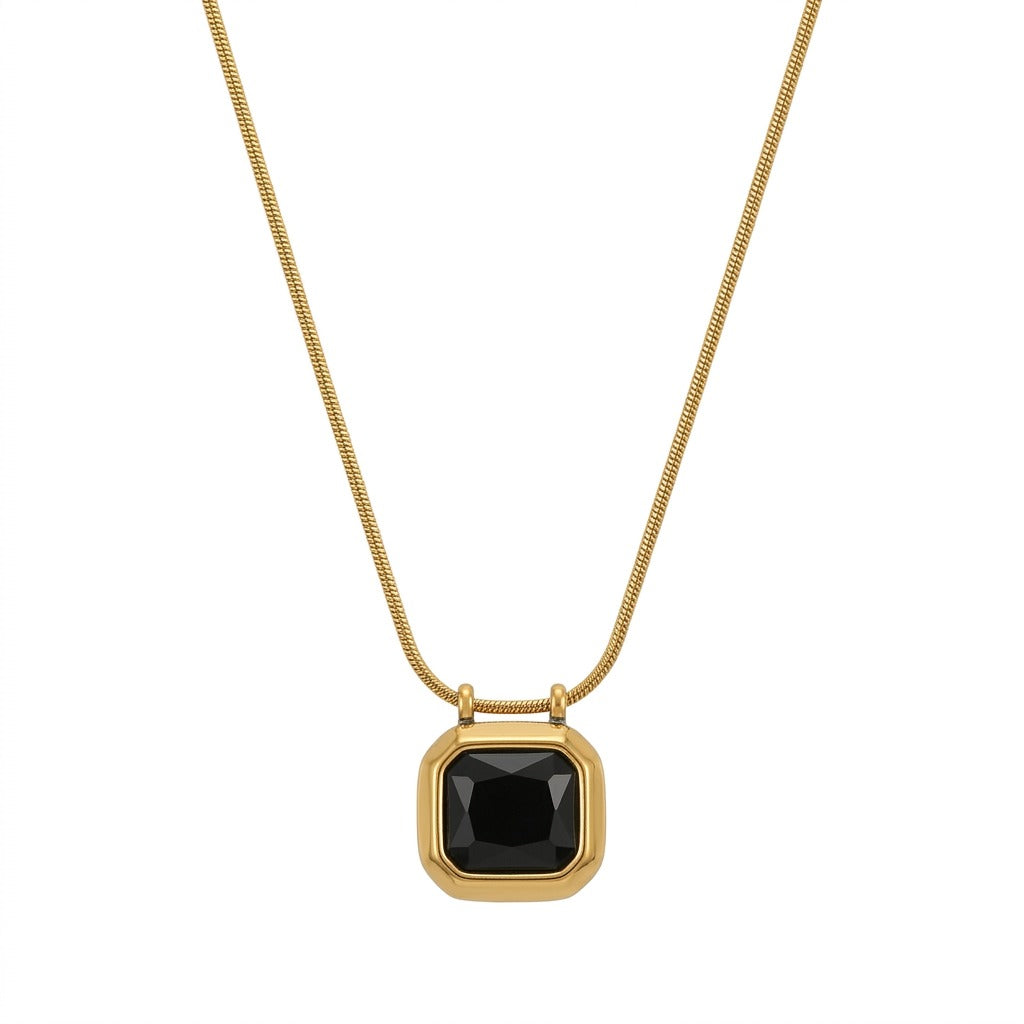 A gold necklace with a delicate snake chain holding a square-cut black gemstone pendant with faceted edges. The black stone is encased in a smooth, thick gold bezel frame, centered on a plain white background with a dark frame around the image.