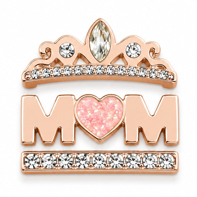 Zoomed-out view of a rose gold-toned decorative accessory set featuring a crystal tiara, pink heart, MOM lettering, and crystal-studded bar details on a white background.