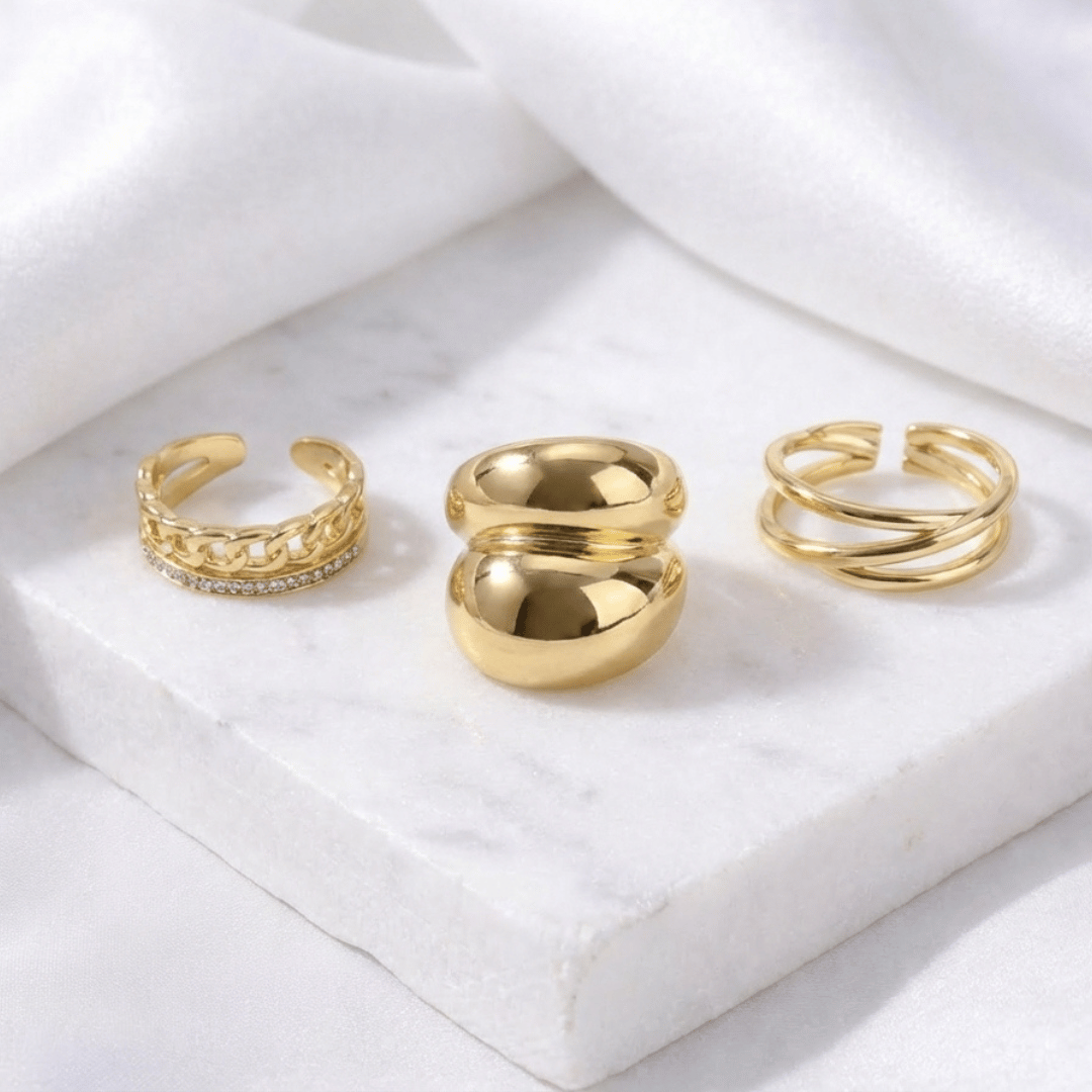 A three-piece gold ring stack featuring a criss-cross entwine band, a structured interlink design, and a bold fluid spiral statement ring.